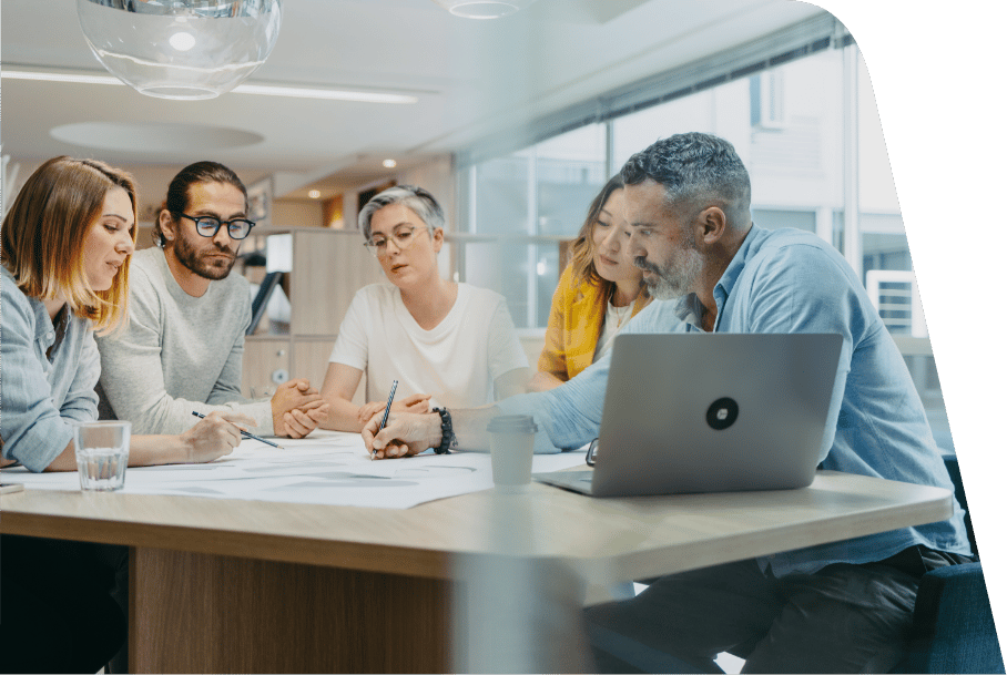 a group of people sitting at a table looking at a laptop