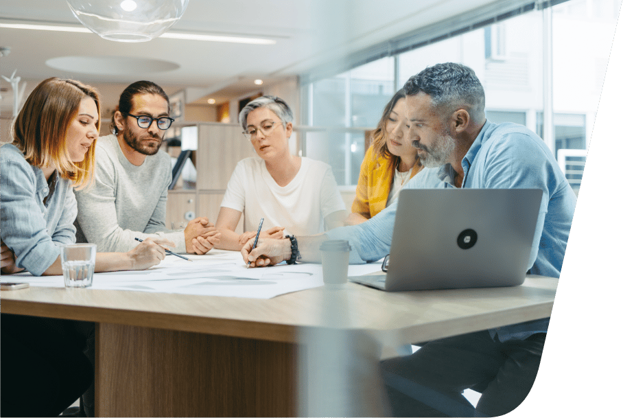 a group of people sitting at a desk looking at a laptop a group of people sitting at a desk looking at a laptop