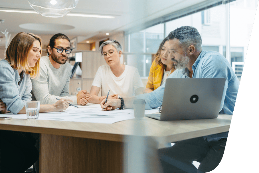 a group of people sitting at a desk looking at a laptop