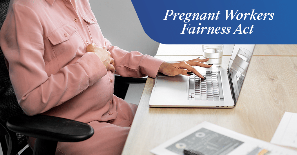a pregnant woman sitting at a table using a laptop